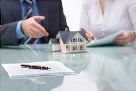 Two people talking to each other about the house with a pen, ballpen, and mini house above the table